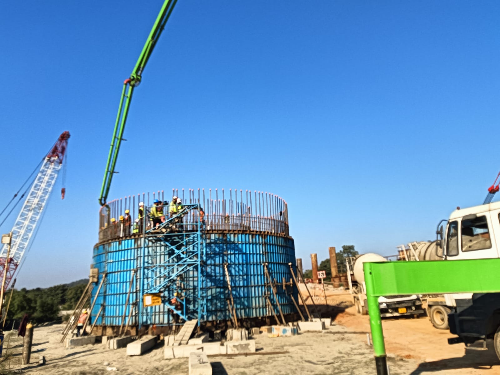 Daytime construction of large cylindrical structure with blue formwork
