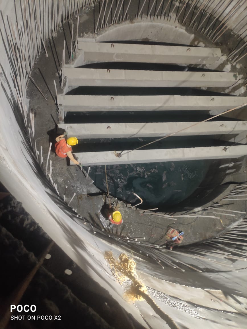 Workers inside deep well construction showing interior concrete work and safety protocols